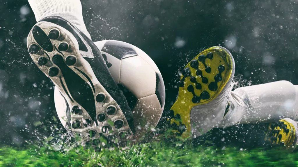Sports washing - Football scene at night match with close up of a soccer shoe hitting the ball with power by alphaspirit