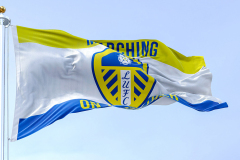 Leeds, UK, Oct. 2022: The Leeds United flag waving in the wind. White shield with blue and yellow stripes, white rose, and LUFC in blue. Rippled fabric. Realistic 3D illustration render. ©rarrarorro/123RF.COM